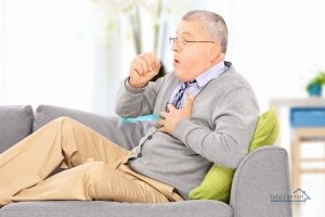 Man seated on a sofa coughing