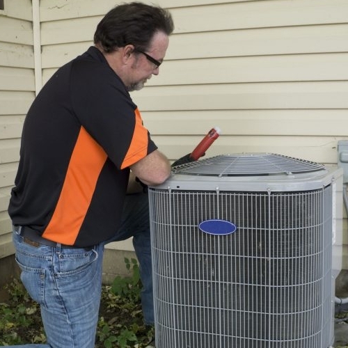 Repairman checking outside air conditioning unit for voltage