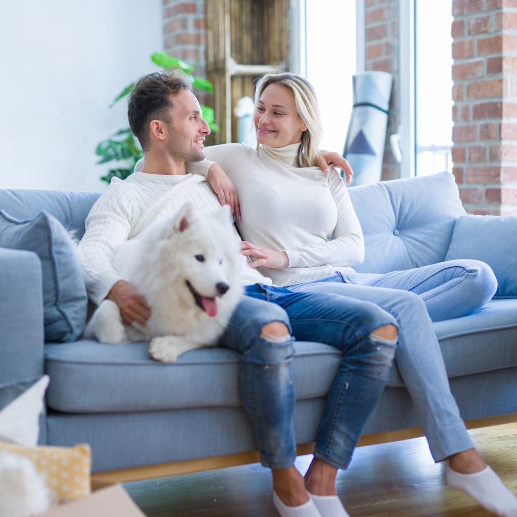 Young couple with dog sitting on the sofa at home
