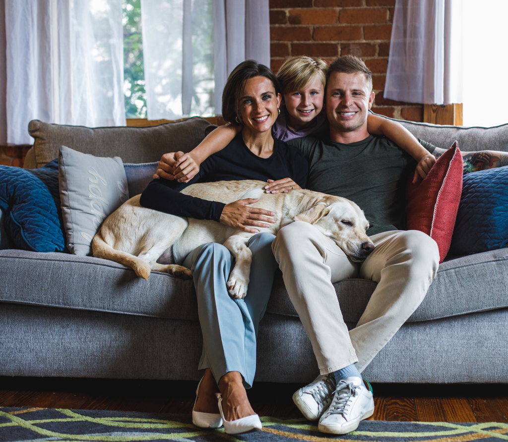 Mother, father and son with yellow lab sitting on gray couch