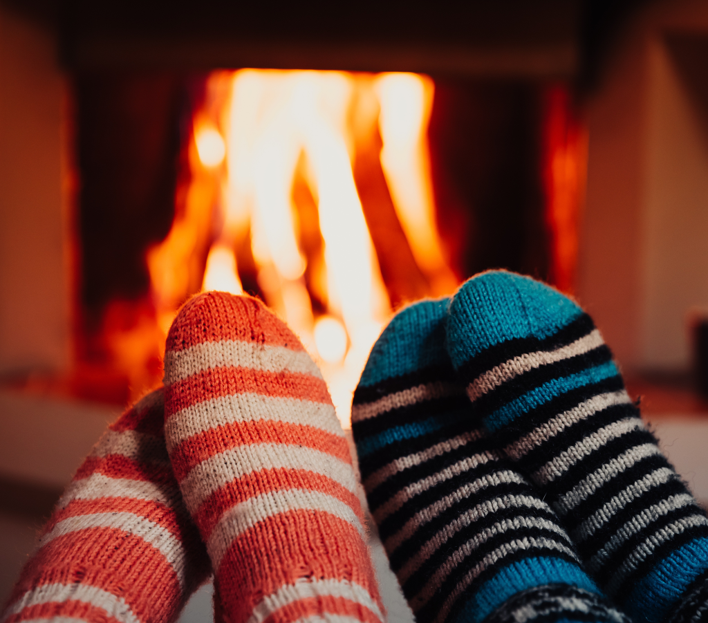 Two pairs of feet in striped socks warming in front of a fireplace