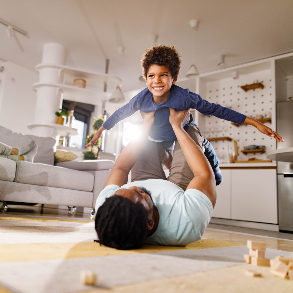 Father and boy having fun while playing on floor in the living room.