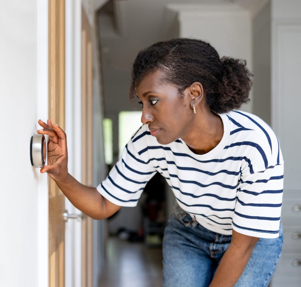 Woman adjusting indoor thermostat
