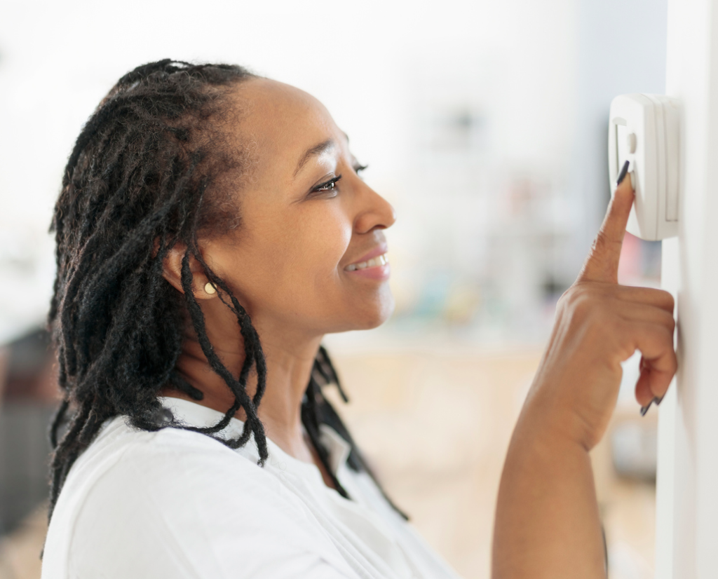 Lady adjusting the climate control panel on the wall thermostat